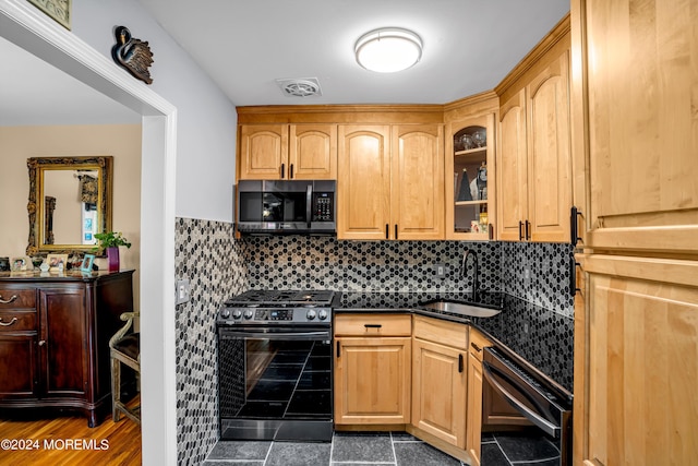 kitchen featuring dark countertops, visible vents, appliances with stainless steel finishes, glass insert cabinets, and a sink