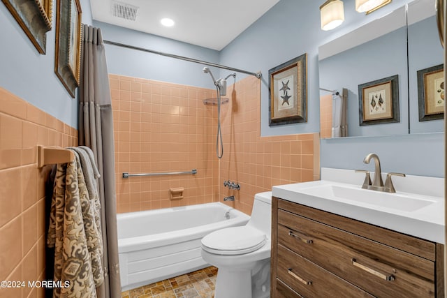 full bathroom featuring visible vents, toilet, shower / tub combo with curtain, vanity, and tile walls