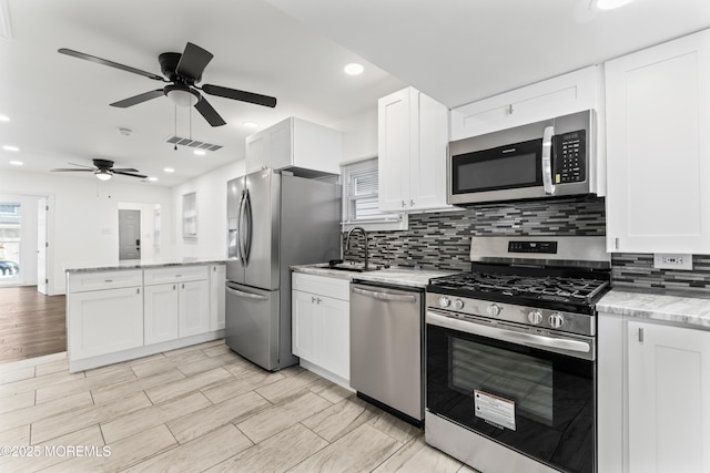 kitchen featuring appliances with stainless steel finishes, backsplash, visible vents, and white cabinetry