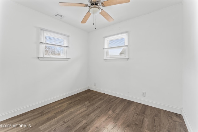 empty room featuring ceiling fan, dark wood-style flooring, visible vents, and baseboards