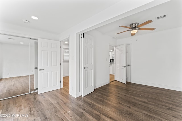 empty room featuring a ceiling fan, wood finished floors, visible vents, and baseboards