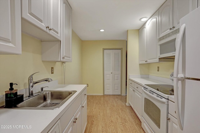 kitchen featuring light wood finished floors, light countertops, white cabinets, a sink, and white appliances