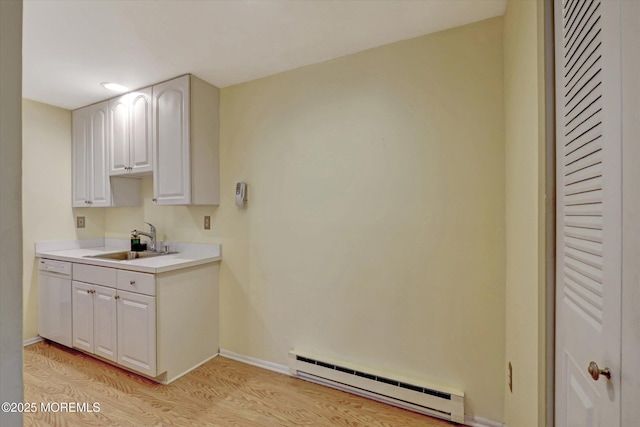 kitchen with light wood finished floors, dishwasher, light countertops, a baseboard heating unit, and a sink