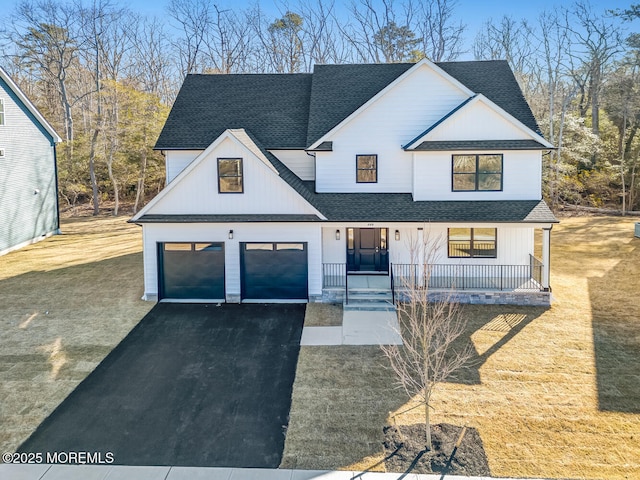 modern inspired farmhouse with a porch, aphalt driveway, an attached garage, a shingled roof, and board and batten siding