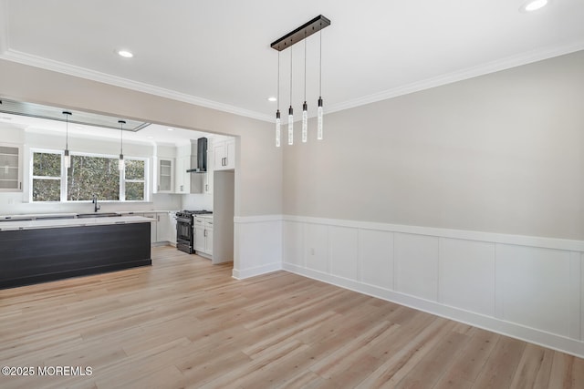 interior space with recessed lighting, a wainscoted wall, a sink, ornamental molding, and light wood finished floors