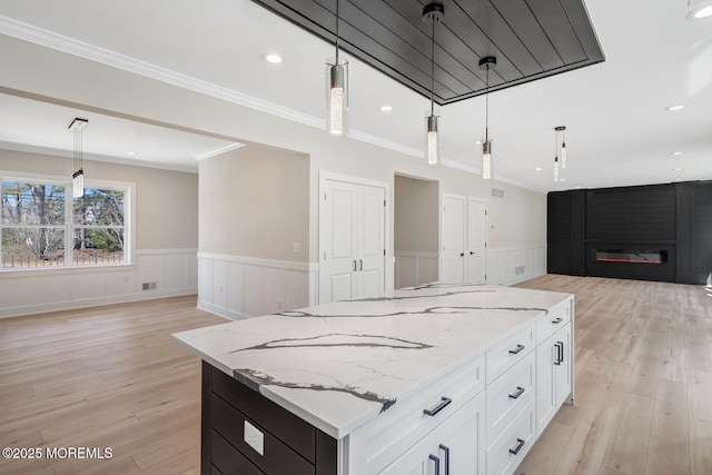 kitchen featuring a large fireplace, open floor plan, and wainscoting