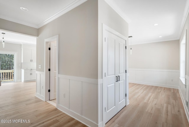 hall featuring light wood-type flooring, wainscoting, and crown molding