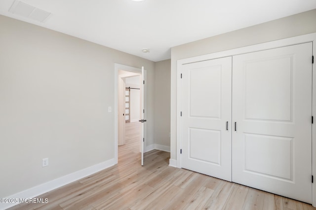 unfurnished bedroom with light wood-style floors, a closet, visible vents, and baseboards