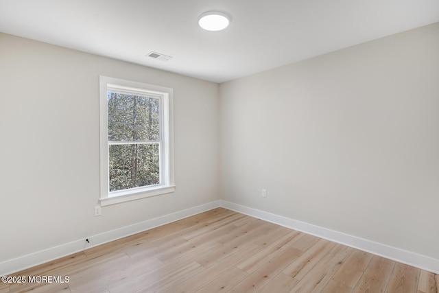 empty room with light wood-type flooring, visible vents, and baseboards