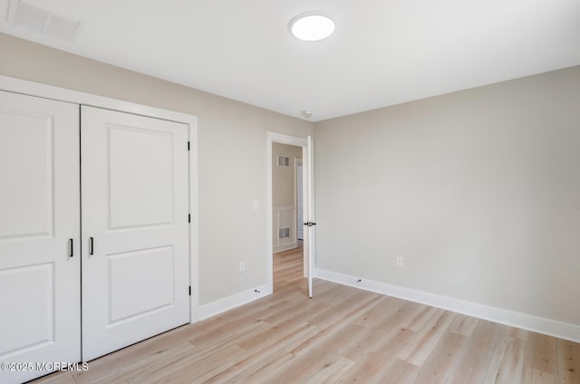 unfurnished bedroom with light wood-style floors, baseboards, visible vents, and a closet