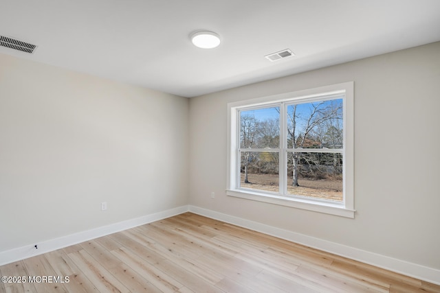 unfurnished room with visible vents, baseboards, and wood finished floors