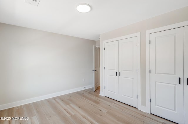 unfurnished bedroom featuring a closet, visible vents, light wood finished floors, and baseboards