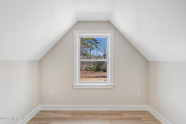 additional living space with lofted ceiling, light wood-style floors, and baseboards