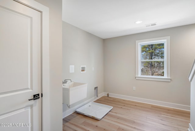 clothes washing area with laundry area, washer hookup, visible vents, light wood-style floors, and baseboards