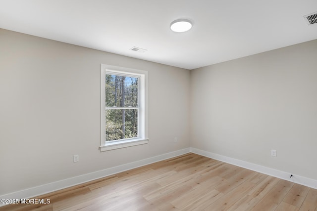 spare room with light wood-style floors, visible vents, and baseboards