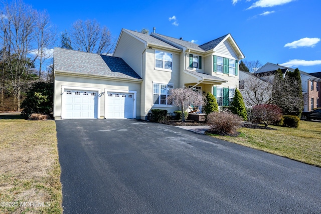 traditional-style house featuring aphalt driveway, a front lawn, and an attached garage