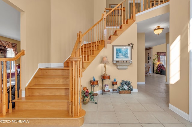 stairway with a high ceiling, tile patterned flooring, and baseboards