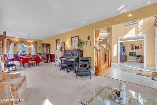 living room with baseboards, stairway, tile patterned floors, an inviting chandelier, and carpet flooring