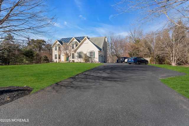 view of front of home featuring solar panels and a front lawn