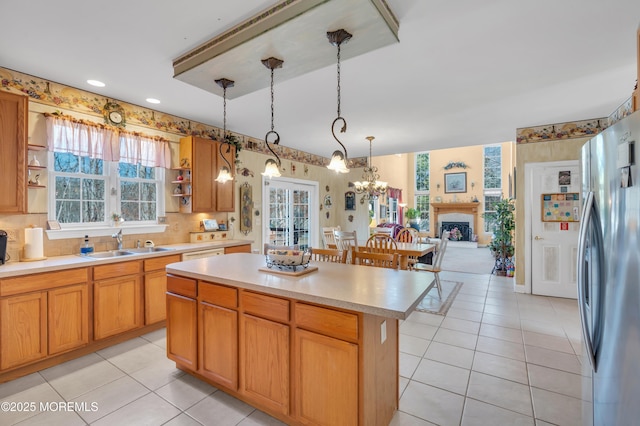 kitchen with a kitchen island, freestanding refrigerator, light countertops, a sink, and light tile patterned flooring