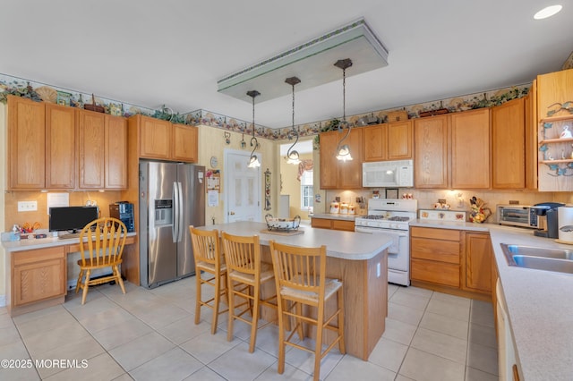 kitchen featuring a center island, built in desk, light countertops, a sink, and white appliances