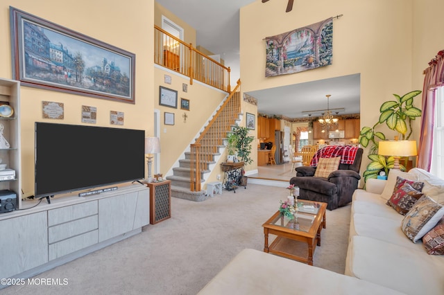 living room featuring carpet floors, stairs, a notable chandelier, and a towering ceiling