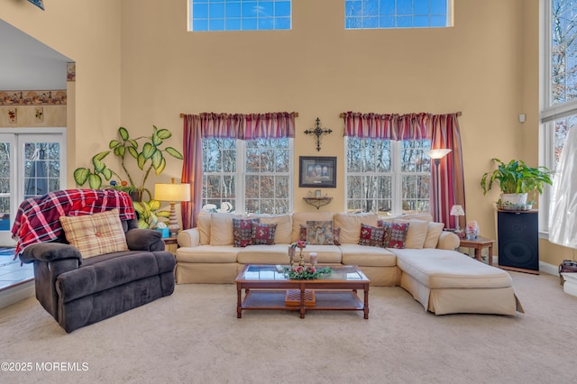 living area featuring carpet flooring, a towering ceiling, and baseboards