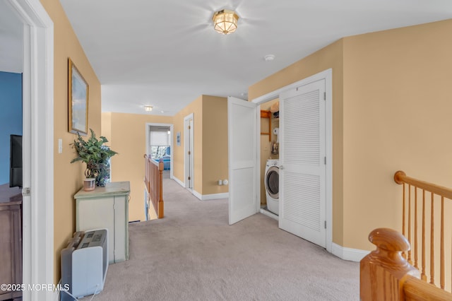 corridor with carpet, washer / clothes dryer, baseboards, and an upstairs landing