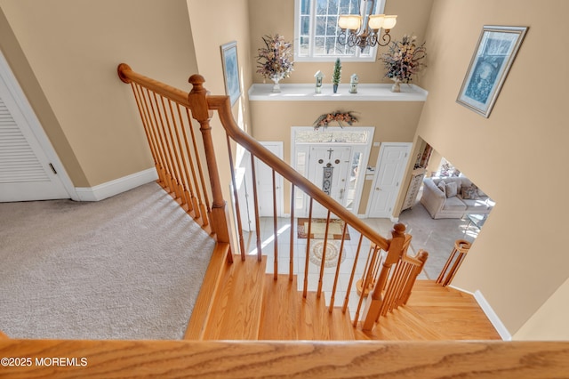 staircase with a chandelier, wood finished floors, and baseboards