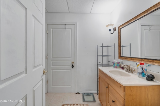 bathroom featuring tile patterned flooring, a drop ceiling, and vanity