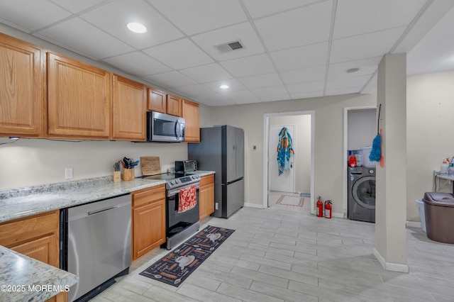 kitchen featuring stainless steel appliances, washer / clothes dryer, a paneled ceiling, and visible vents