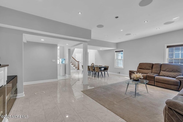 living room featuring marble finish floor, a healthy amount of sunlight, stairs, and baseboards