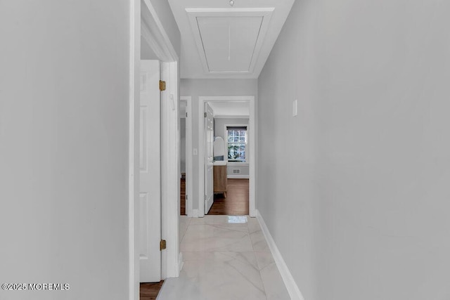 hall featuring marble finish floor, attic access, and baseboards