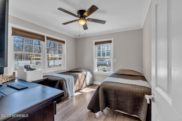 bedroom with baseboards, ceiling fan, crown molding, and light wood finished floors