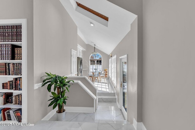 corridor with a skylight, baseboards, marble finish floor, and high vaulted ceiling