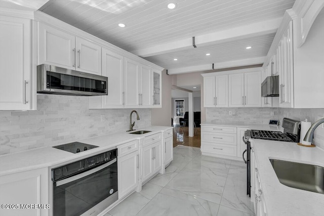 kitchen with beam ceiling, marble finish floor, appliances with stainless steel finishes, and a sink