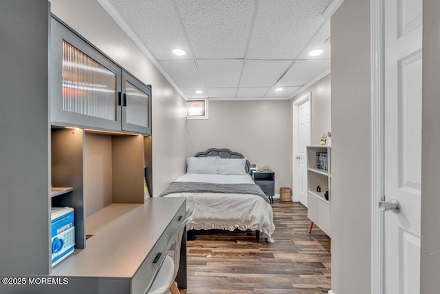 bedroom featuring crown molding, recessed lighting, wood finished floors, and a paneled ceiling