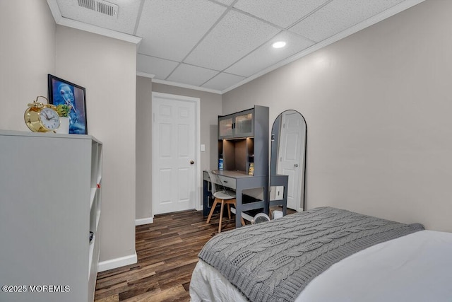 bedroom featuring visible vents, baseboards, wood finished floors, and crown molding