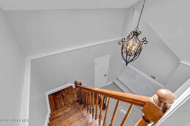 stairway featuring visible vents, baseboards, lofted ceiling, an inviting chandelier, and marble finish floor