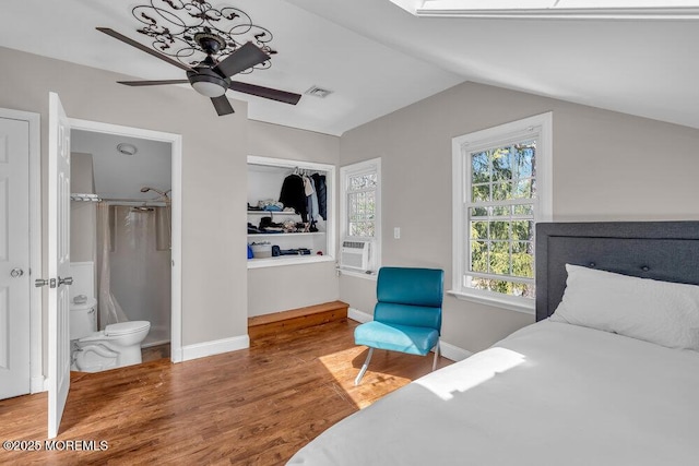 bedroom featuring visible vents, wood finished floors, cooling unit, baseboards, and vaulted ceiling