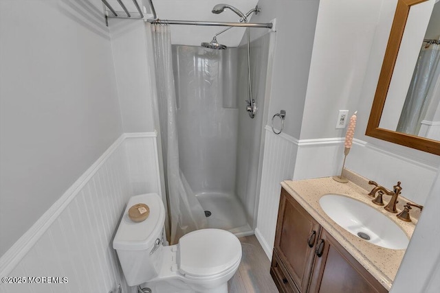 full bathroom with vanity, a shower stall, toilet, and a wainscoted wall