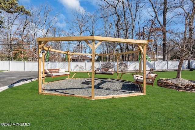 view of jungle gym featuring a lawn, a fenced backyard, and an outdoor fire pit