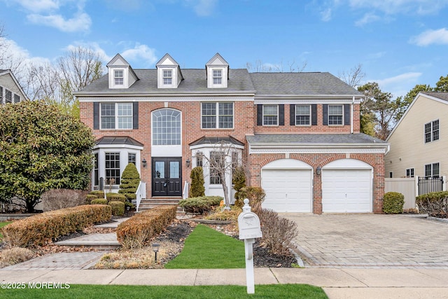 view of front of property with a garage, brick siding, a shingled roof, french doors, and decorative driveway