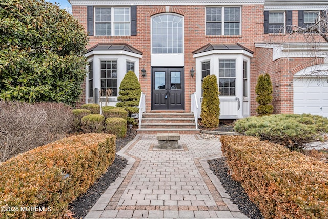 entrance to property featuring a garage, french doors, and brick siding