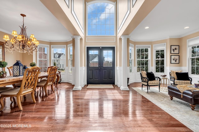 foyer with ornamental molding, wainscoting, decorative columns, and wood finished floors