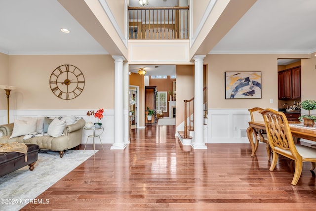 foyer entrance featuring wainscoting, crown molding, stairway, and ornate columns