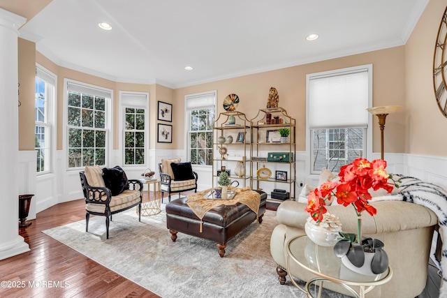 living area featuring recessed lighting, wood-type flooring, wainscoting, and crown molding