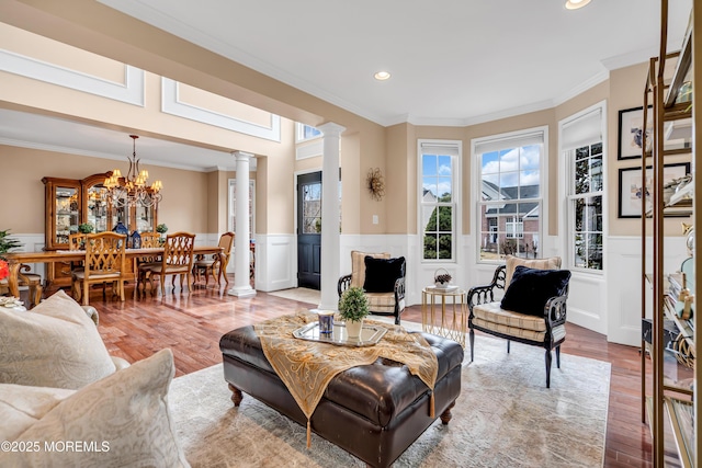 living room with crown molding, wainscoting, decorative columns, and wood finished floors