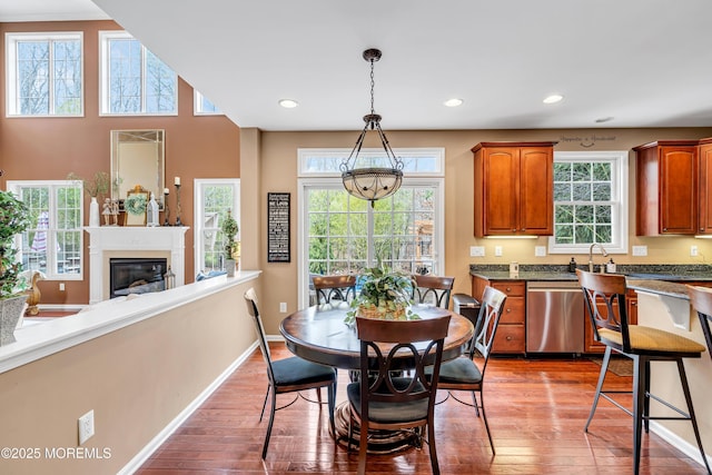 dining room featuring recessed lighting, wood-type flooring, a glass covered fireplace, and baseboards