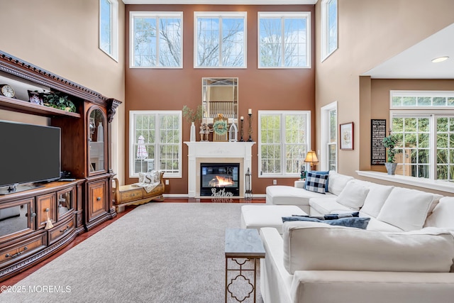 living room featuring a fireplace with flush hearth, plenty of natural light, a high ceiling, and wood finished floors